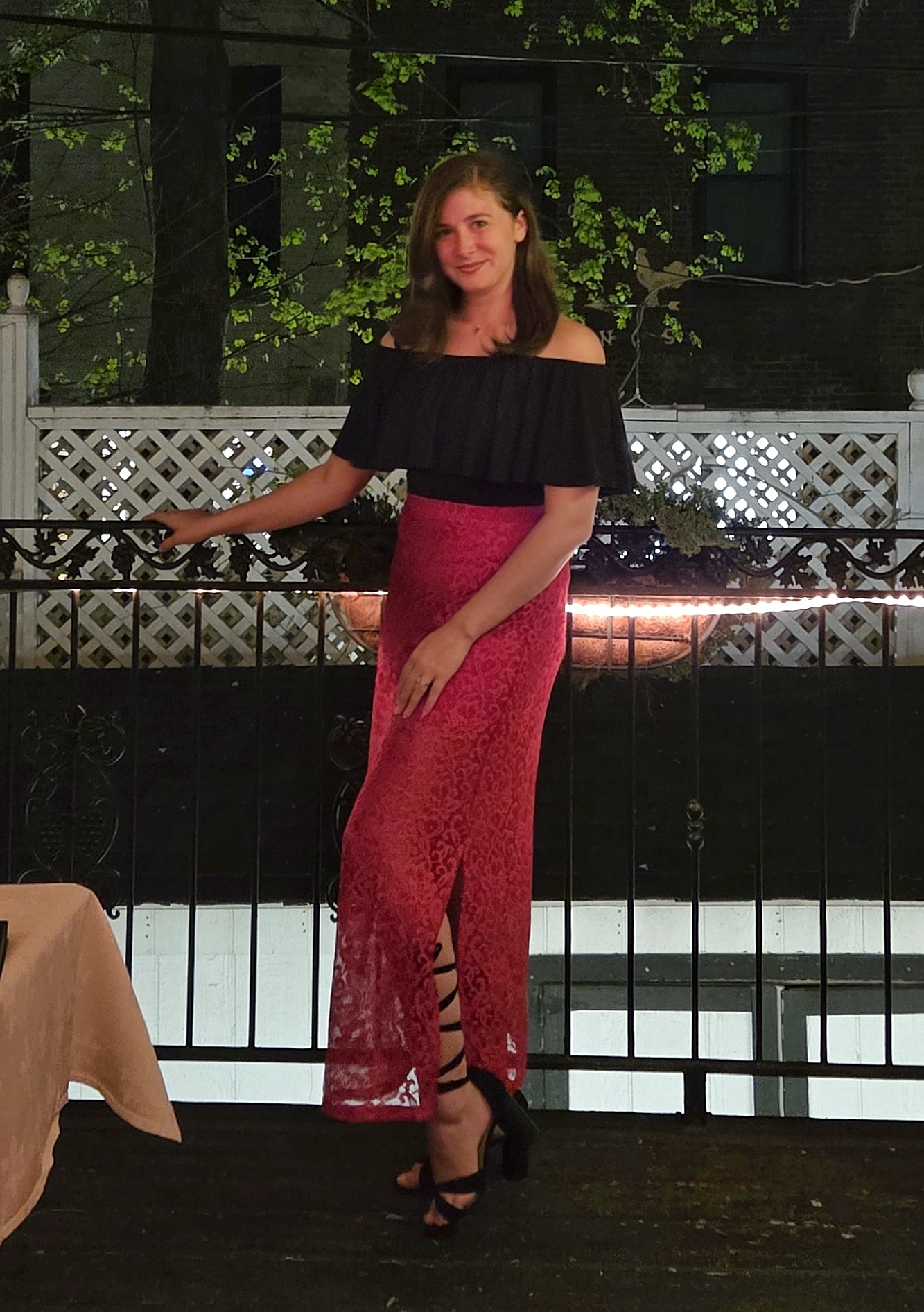 Courtney in a black off-the-shoulder blouse and lace skirt at an evening gathering