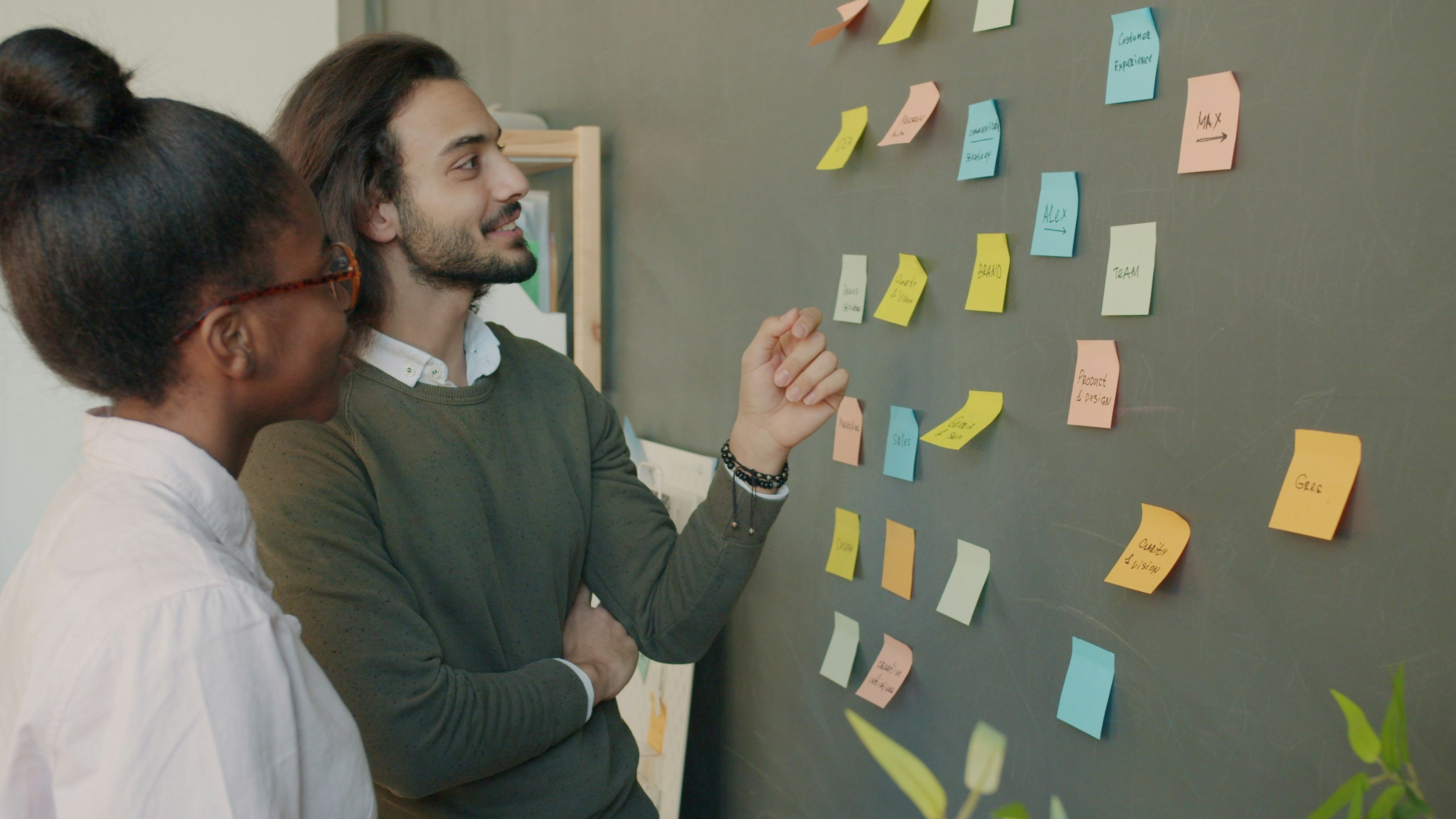 Two colleagues map out ideas together on a wall of planning notes.