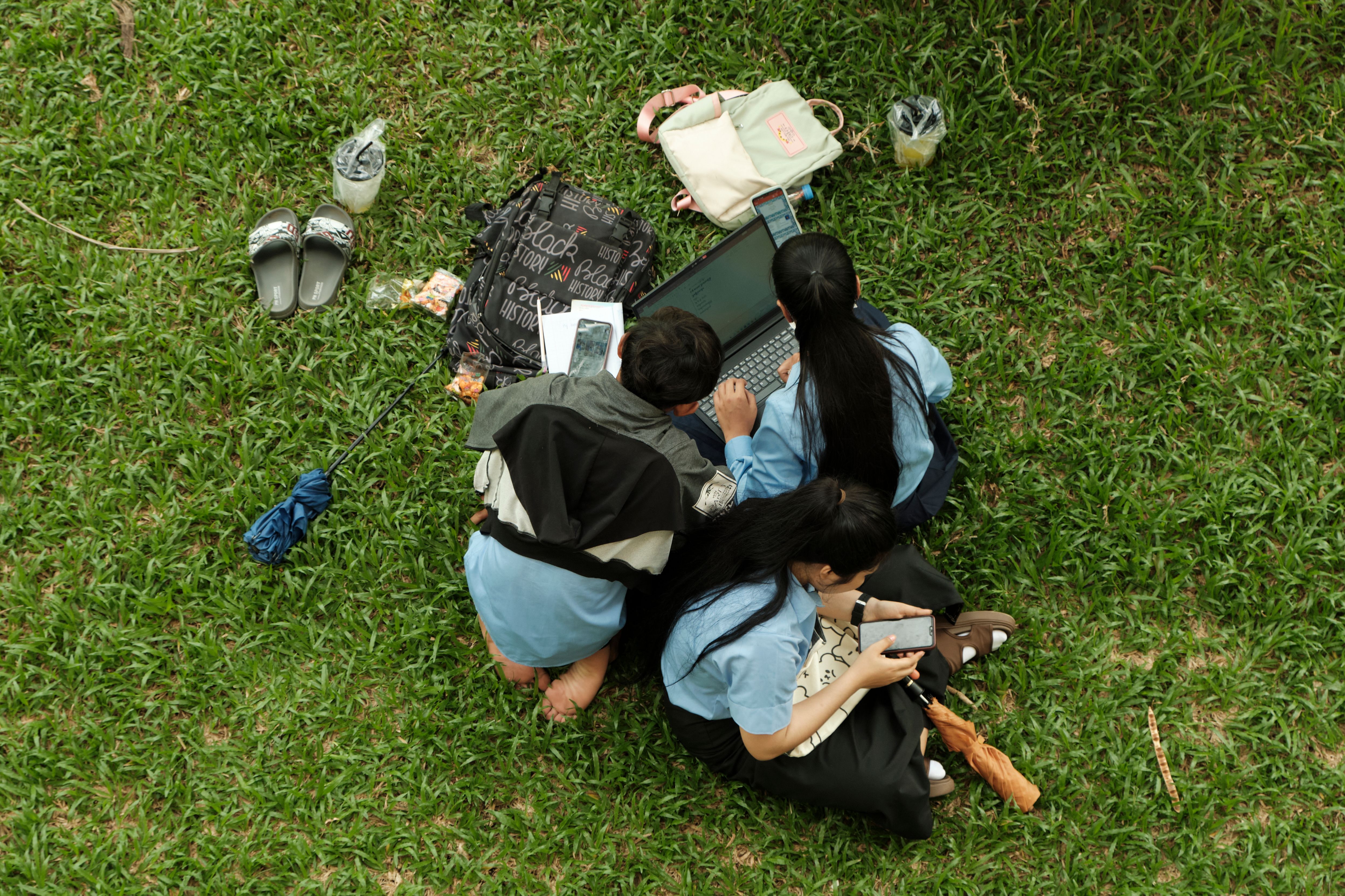 Colleagues working together around a laptop in an outdoor setting, sharing ideas as a team.