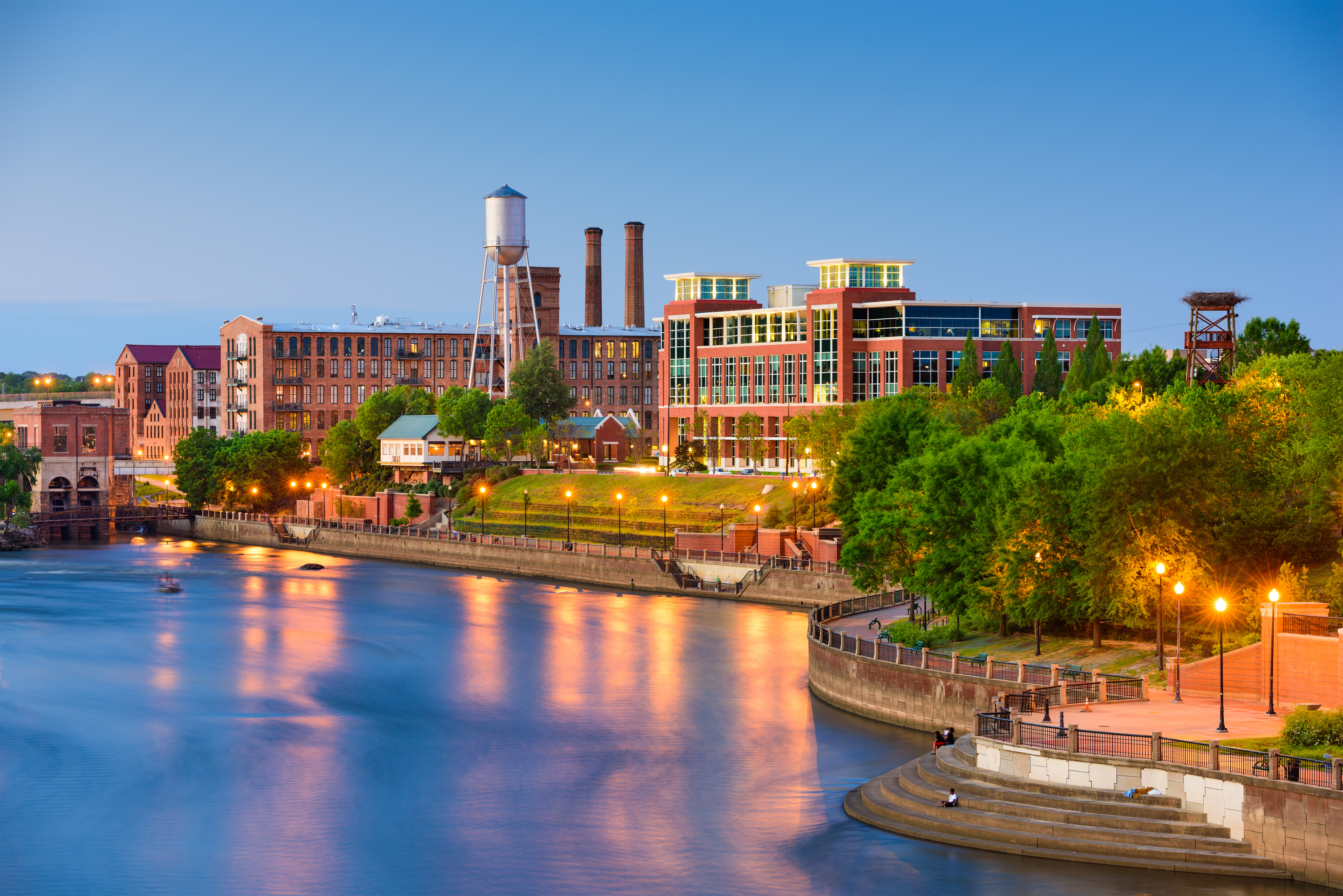 Columbus, Georgia riverfront with historic brick buildings, a water tower, and lights reflected on the river