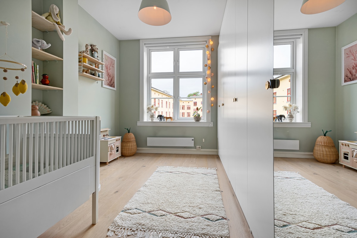 Gender-neutral nursery with warm neutral decor, soft sage accents, and practical storage
