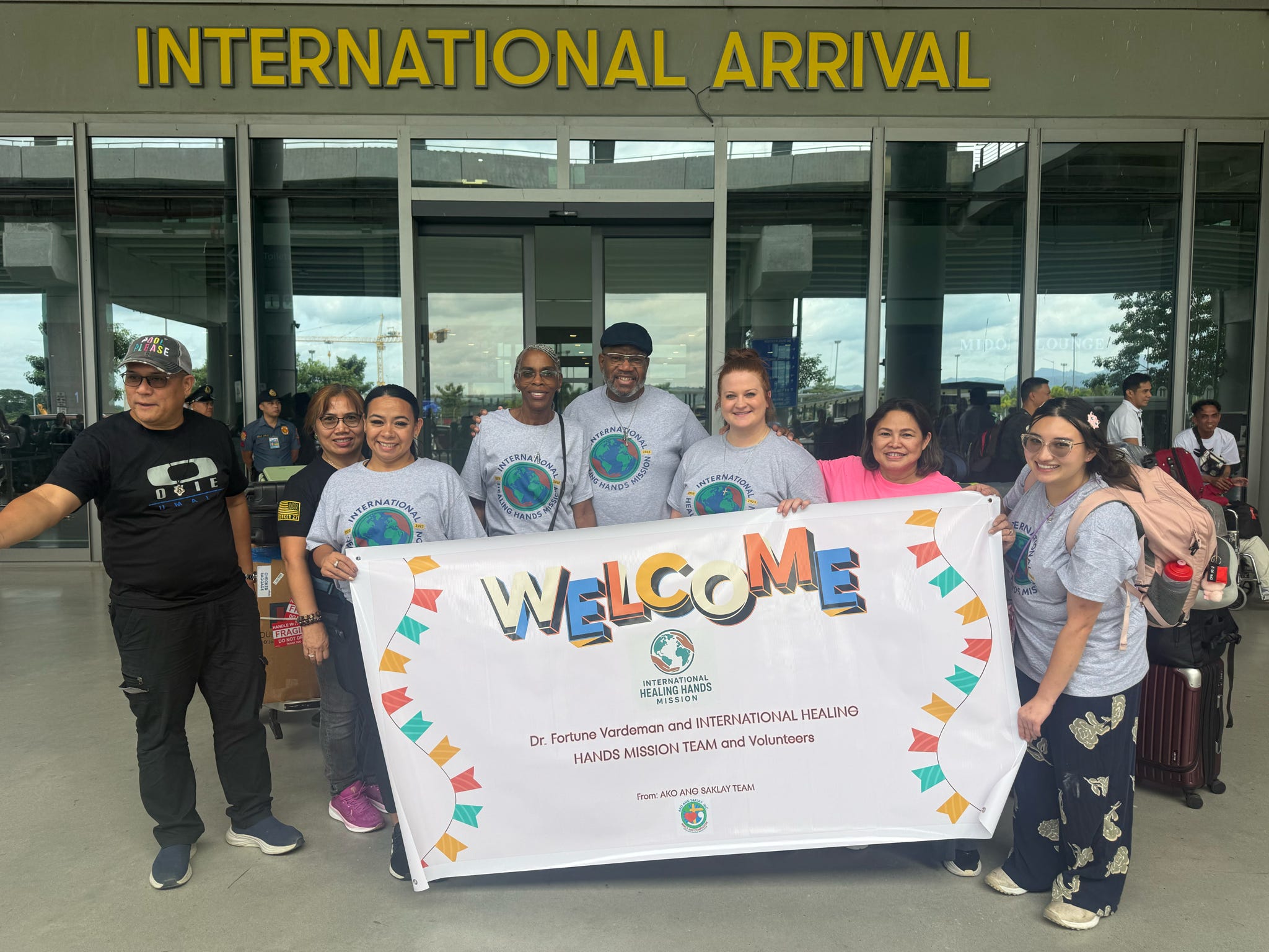 Mission volunteers arriving in the Philippines with a welcome banner