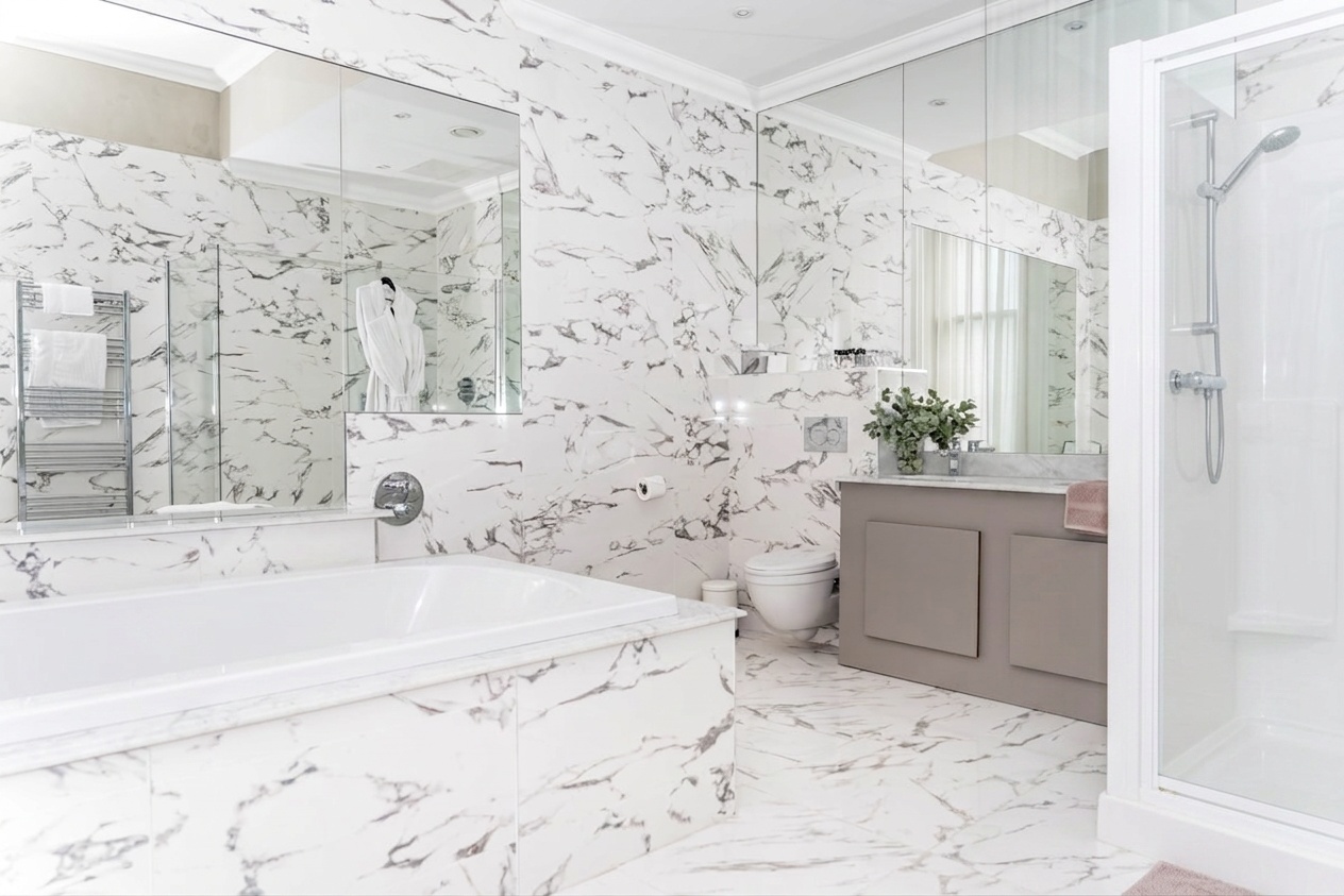Luxury bathroom with a standard white tub and shower, warm ivory towels, and elevated neutral styling