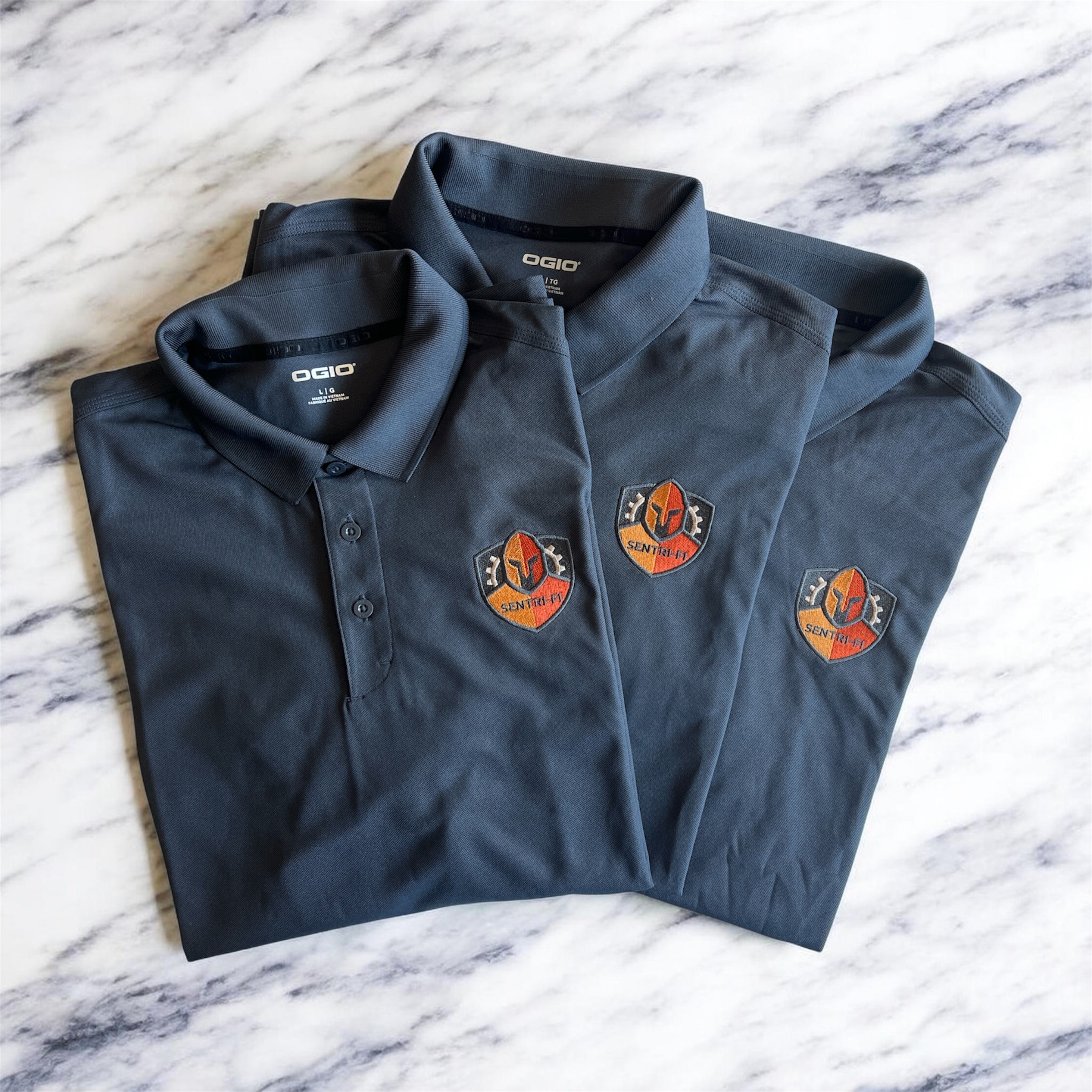 Three folded navy polos with embroidered patches