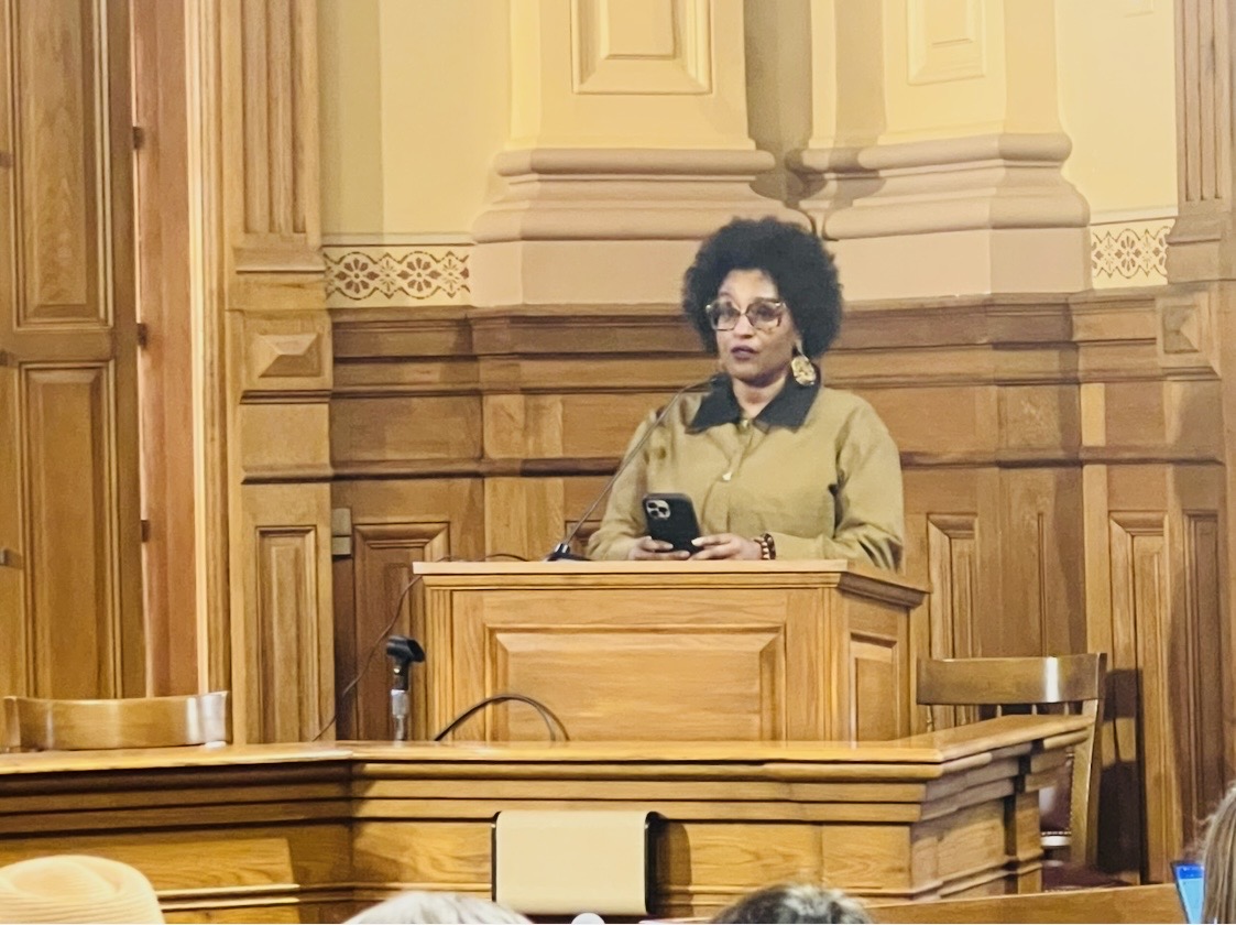 Chanda Santana speaking from a historic wooden lectern
