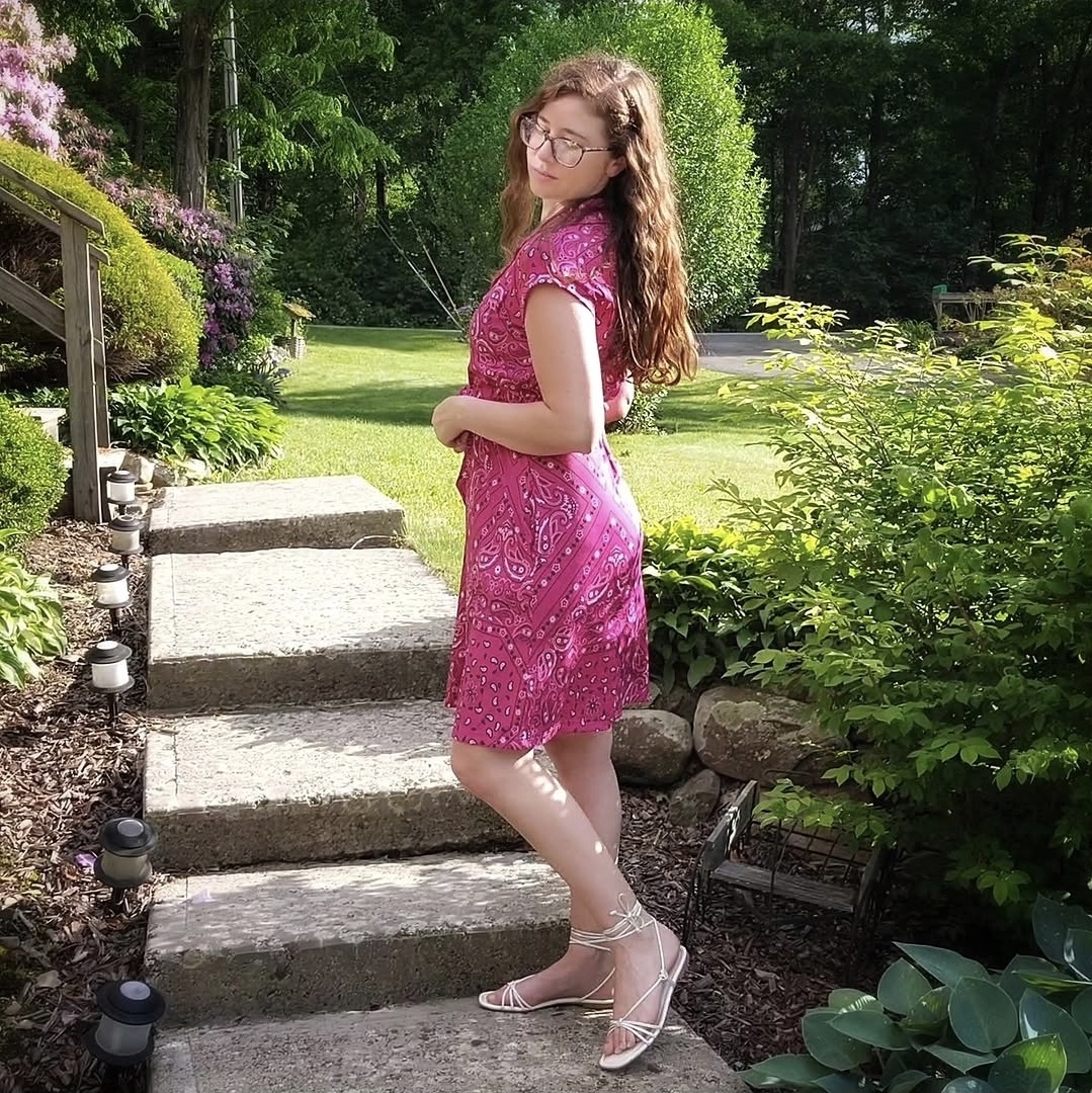 Courtney wearing a teal floral skirt and cardigan by a stone building