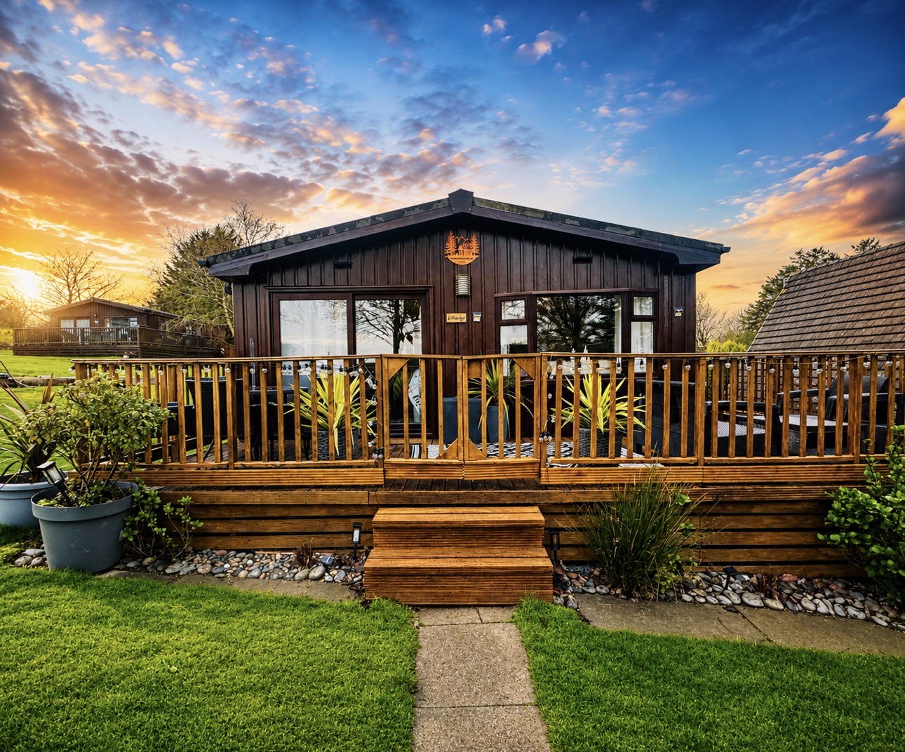 Illustrative Hafan y Môr lodge exterior with a furnished deck at sunset