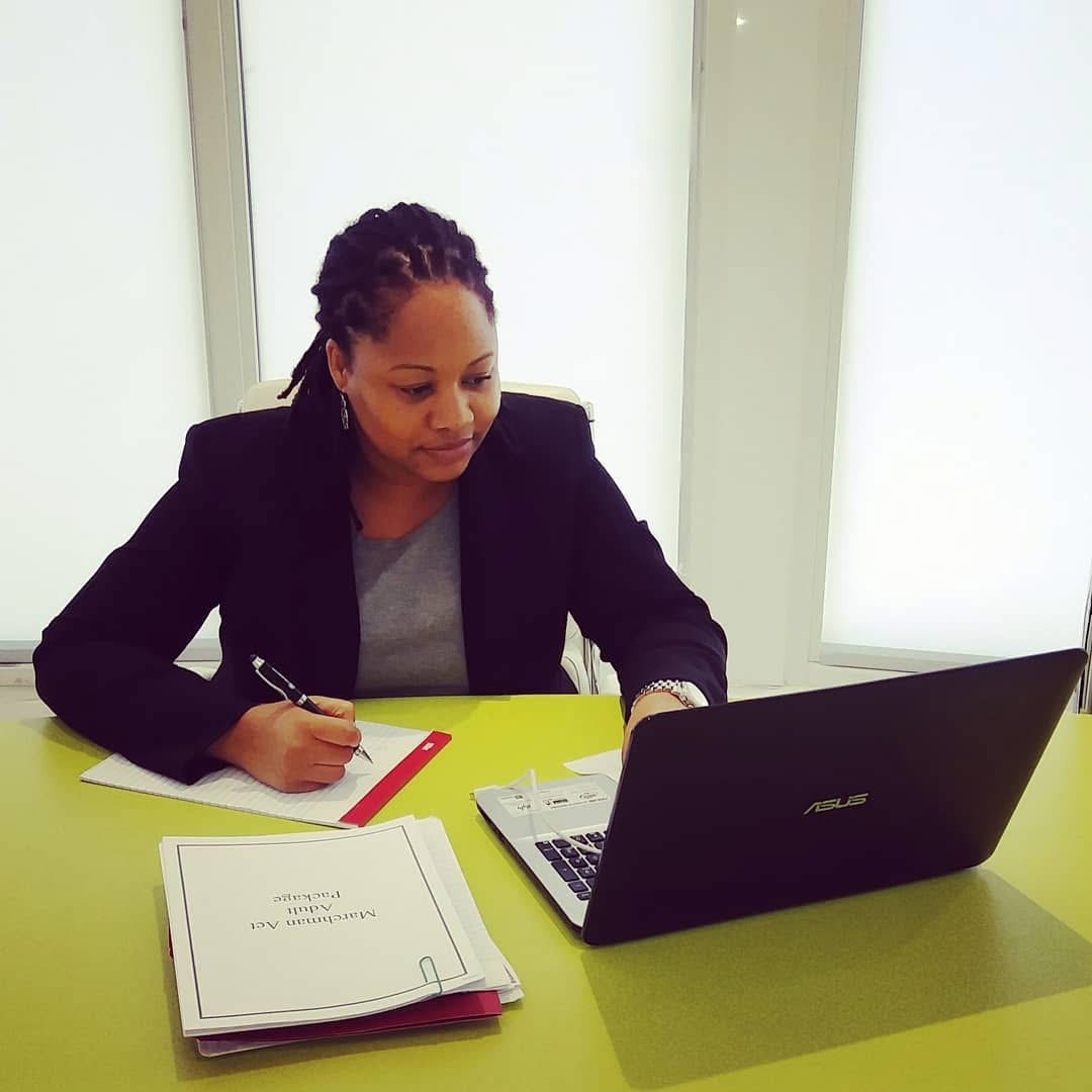 A person reviewing paperwork at a desk beside a laptop.
