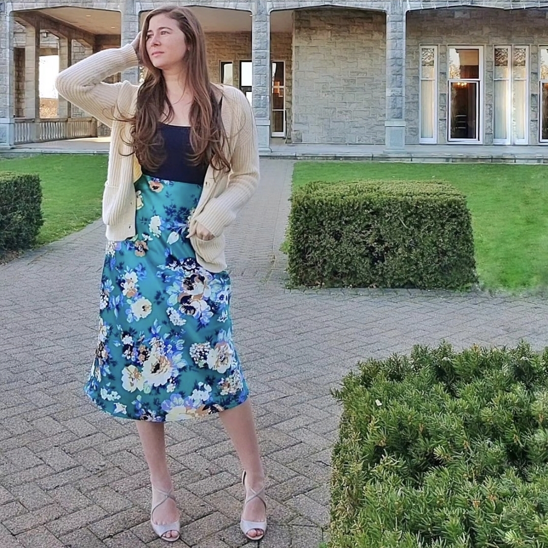 Courtney in a sleeveless green top and floral skirt on a modern stairway