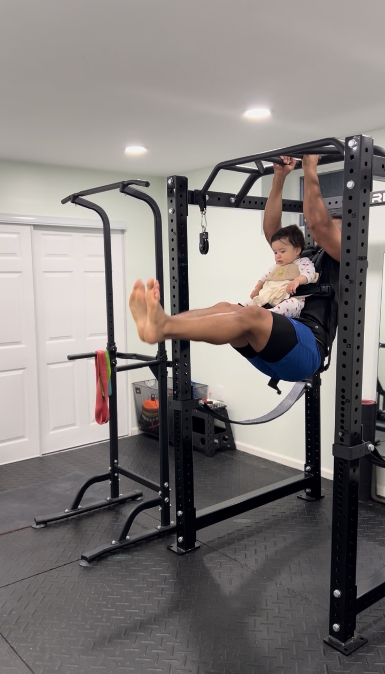 Dad training safely with his child close by in a home gym